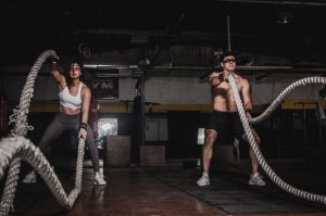 man and woman holding battle ropes