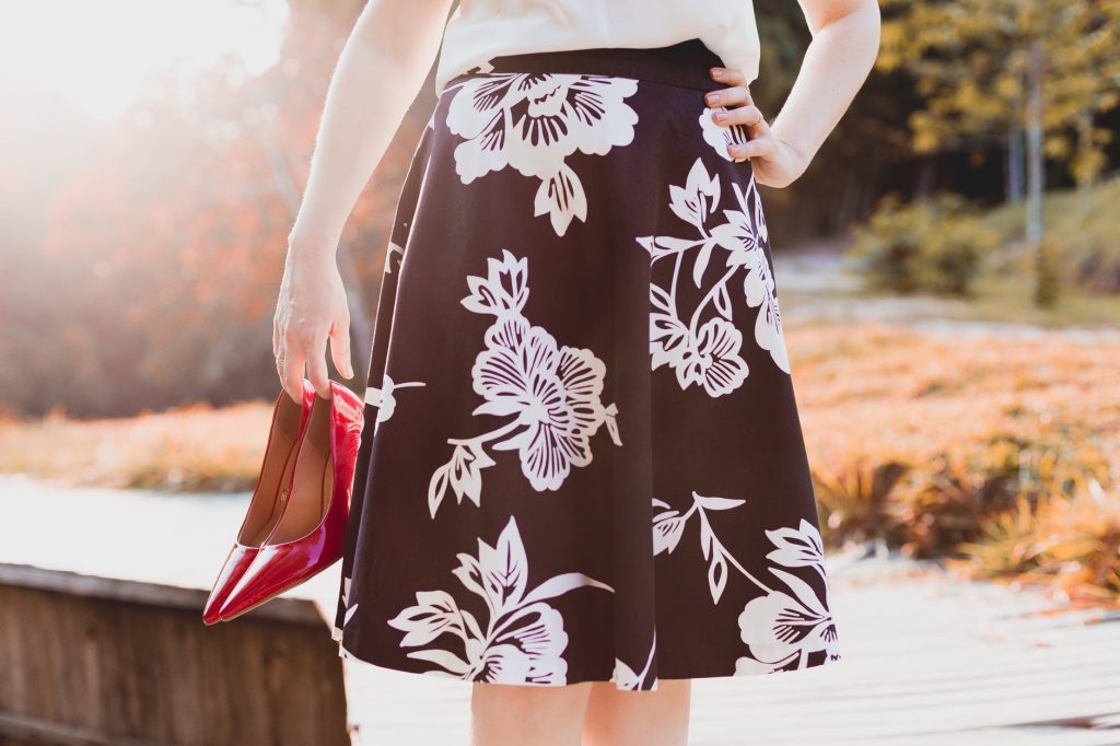 woman wearing skirt holding her shoes