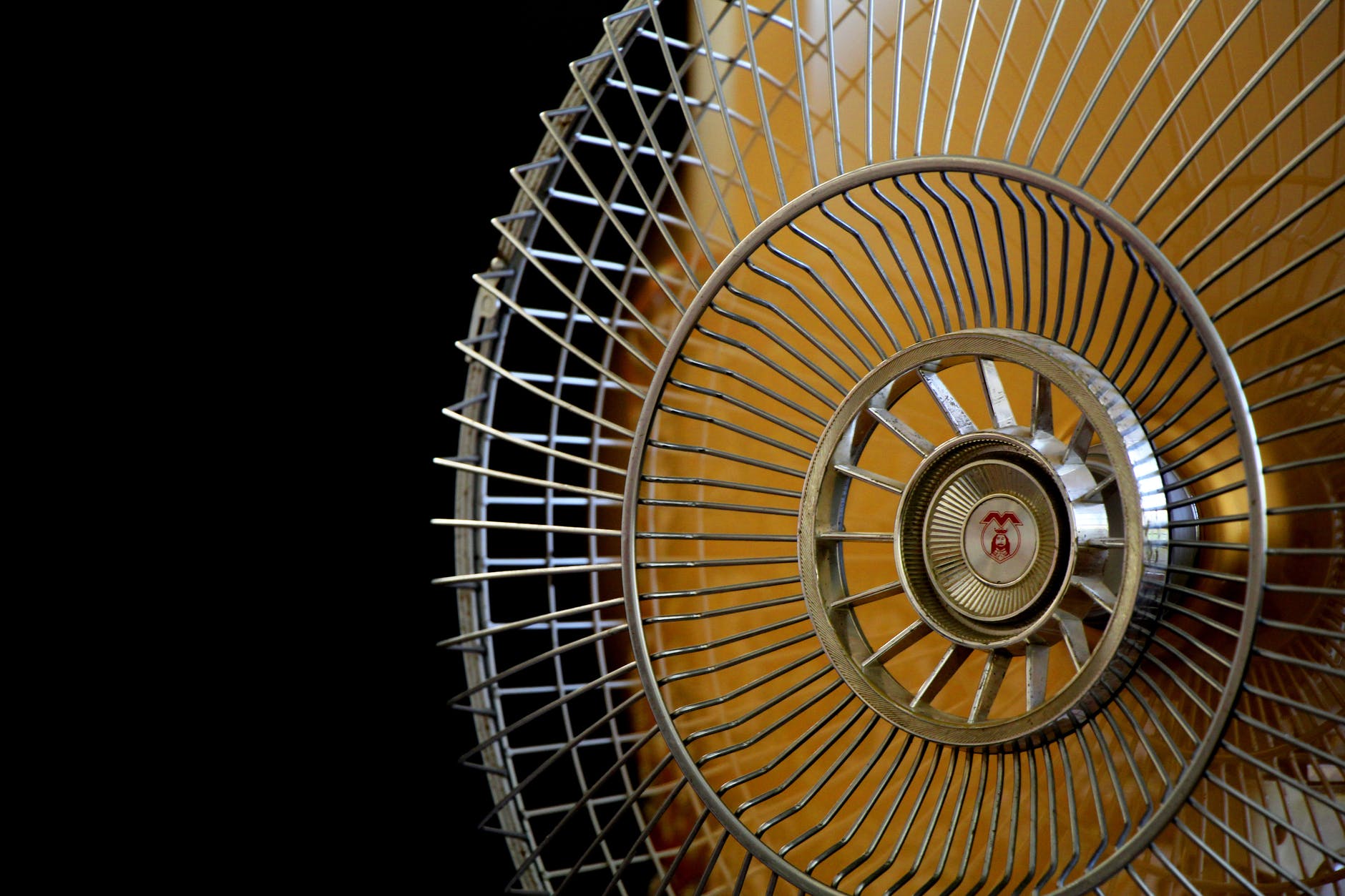 close up photography of gray stainless steel fan turned on surrounded by dark background