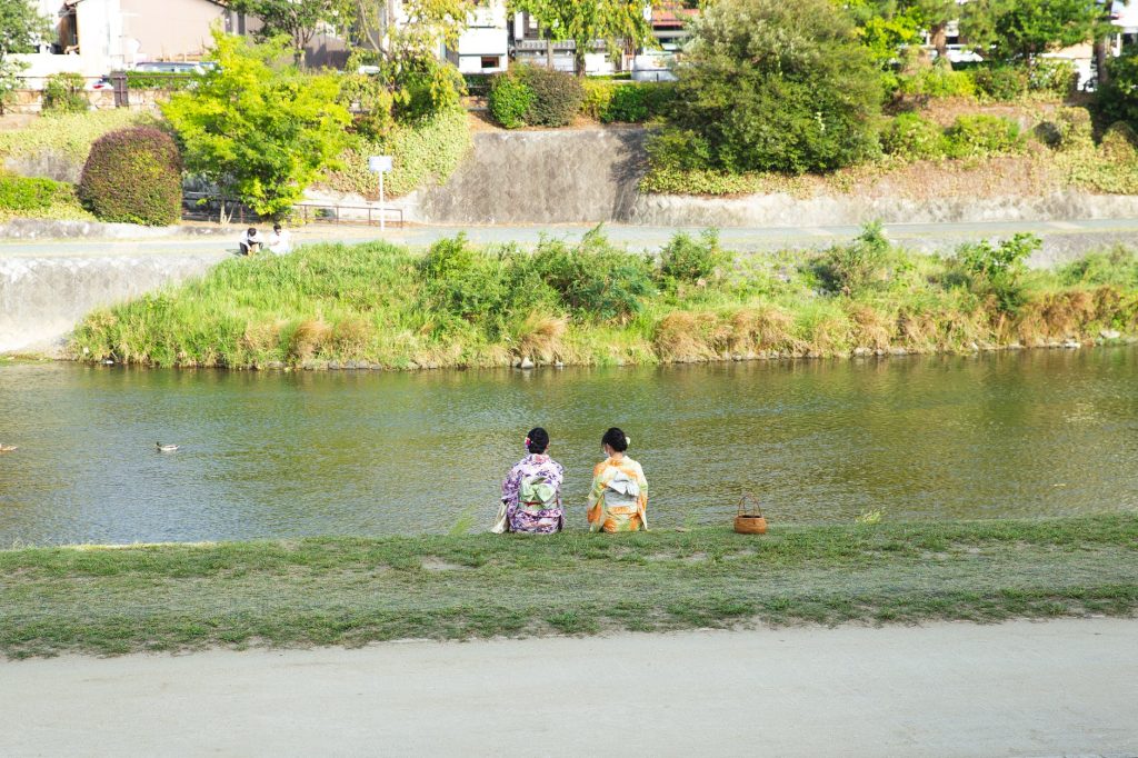 unrecognizable asian women resting on river shore in summer